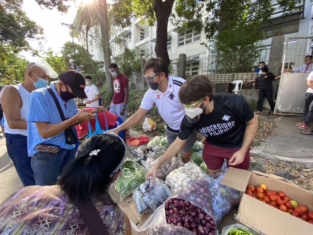 UPMBT coach distributing goods in a community pantry in UP Diliman
